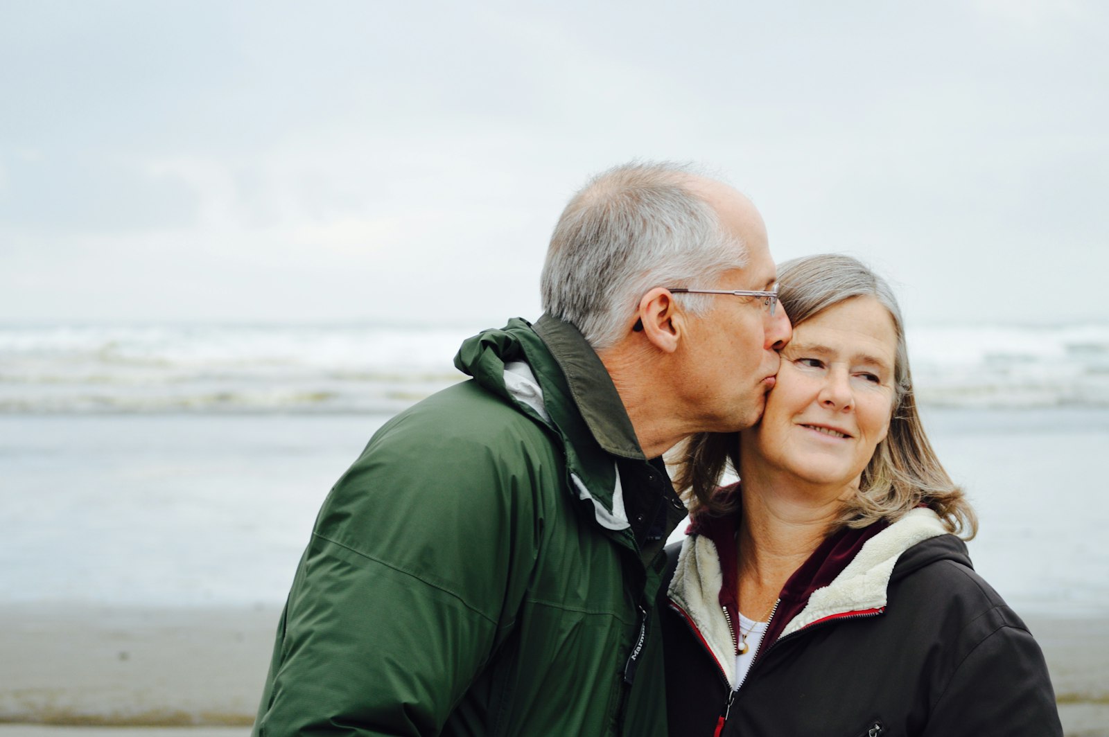 Couple embracing by the sea after menopause