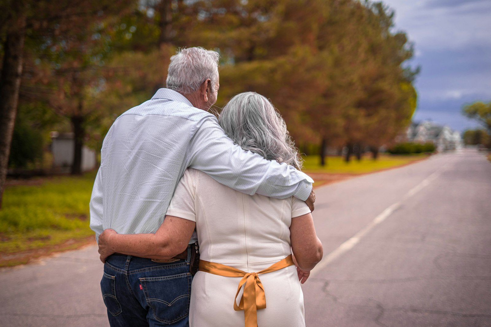 Older couple walking arm in arm down a country road