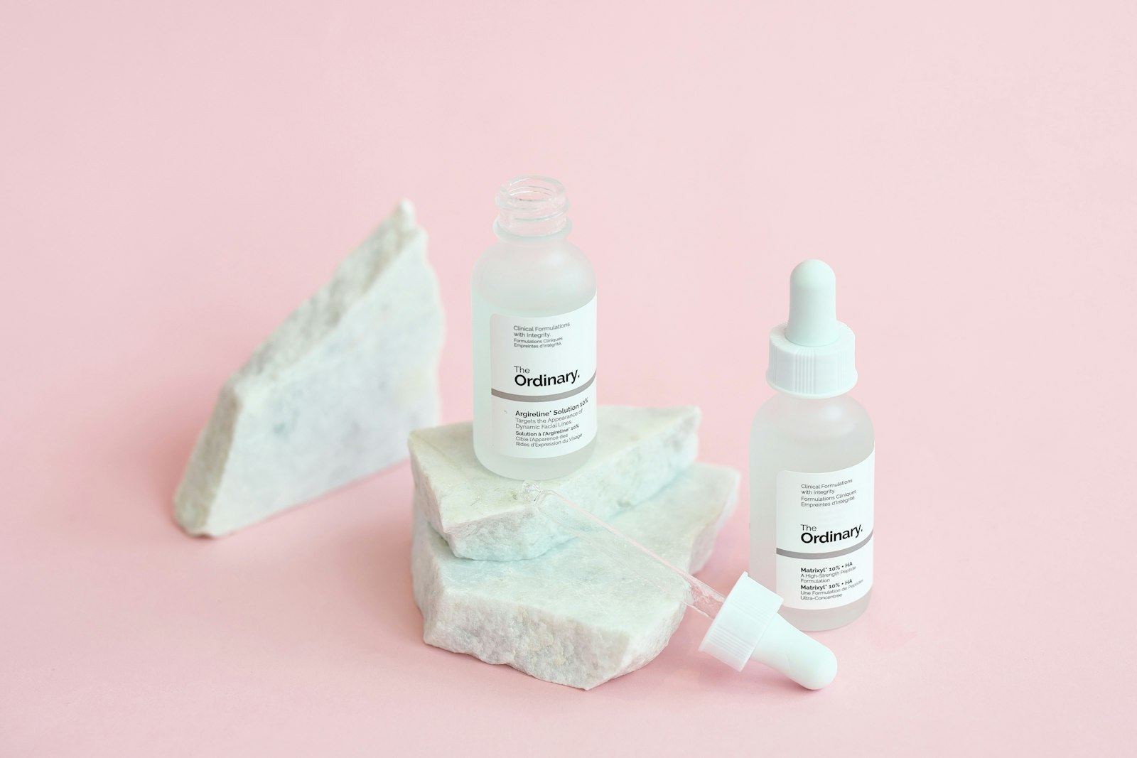 Personal care bottles on marble against a pink background