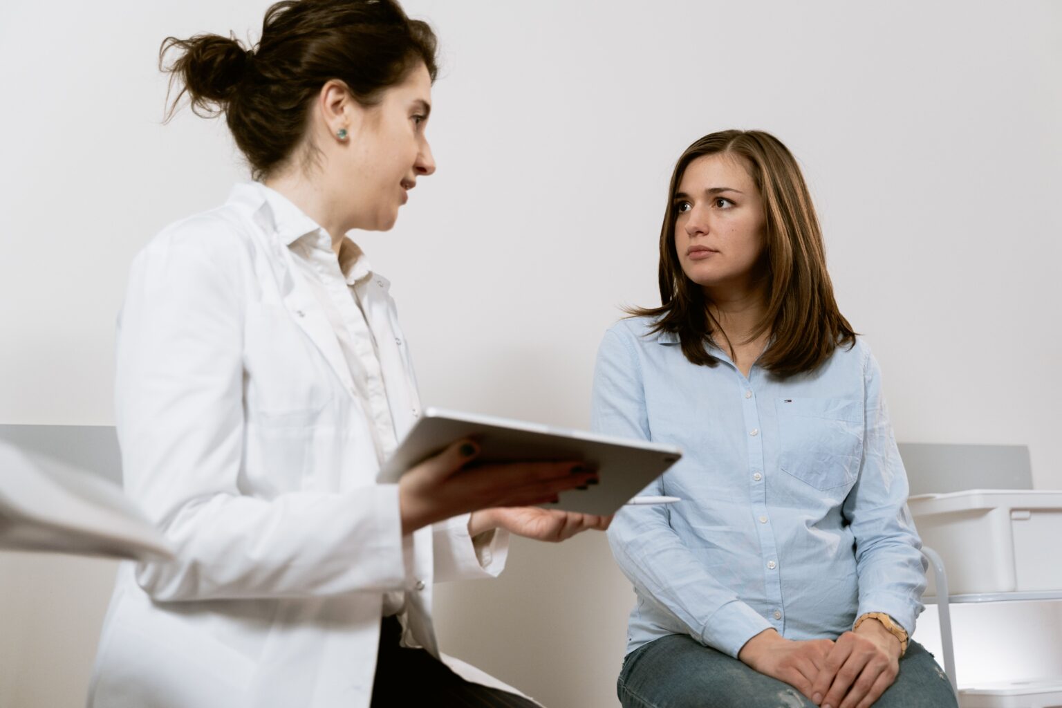 Female doctor with a tablet discussing vaginal dryness treatment options with a woman patient
